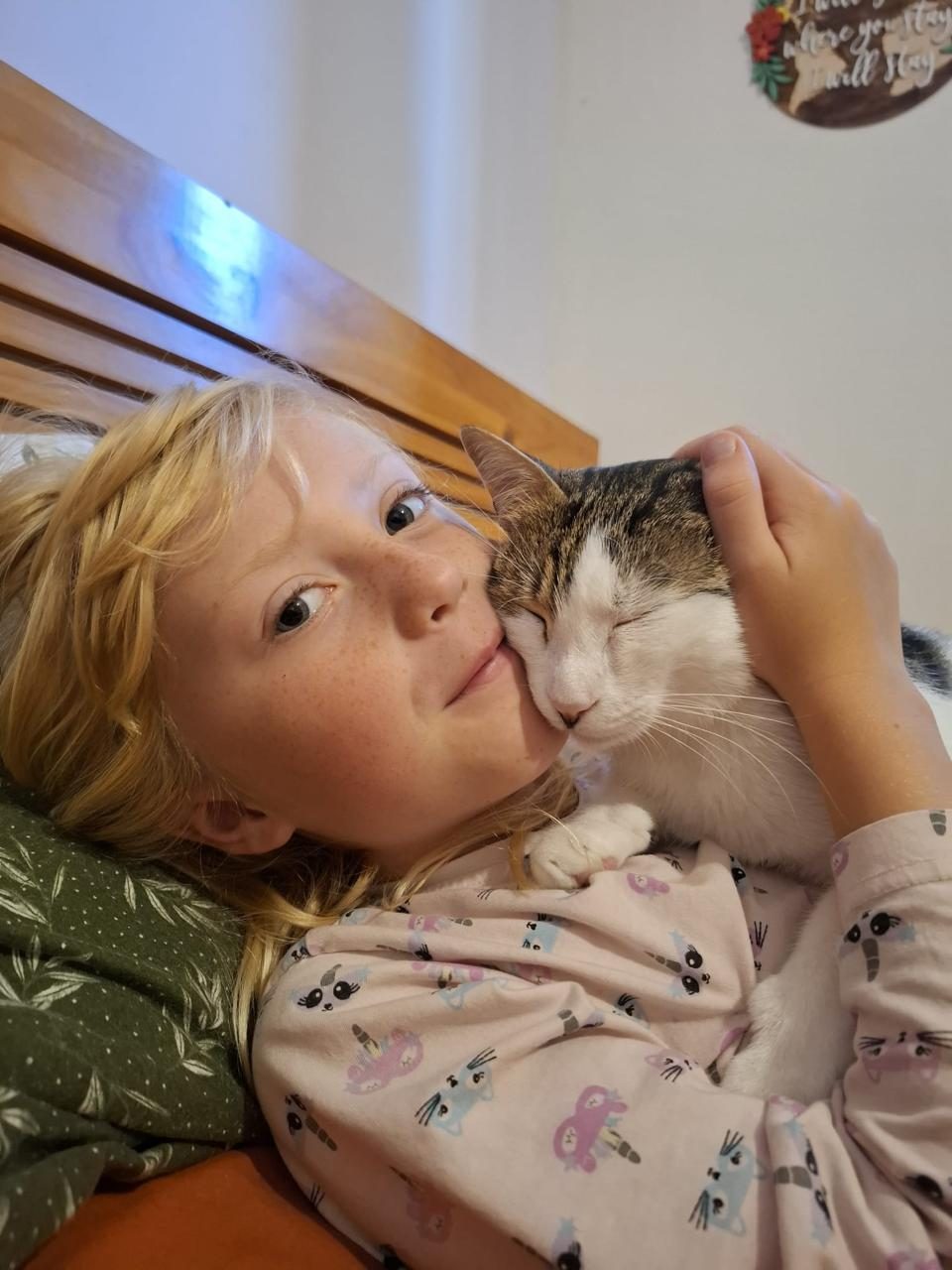 Girl cuddling with her adopted cat cheek-to-cheek